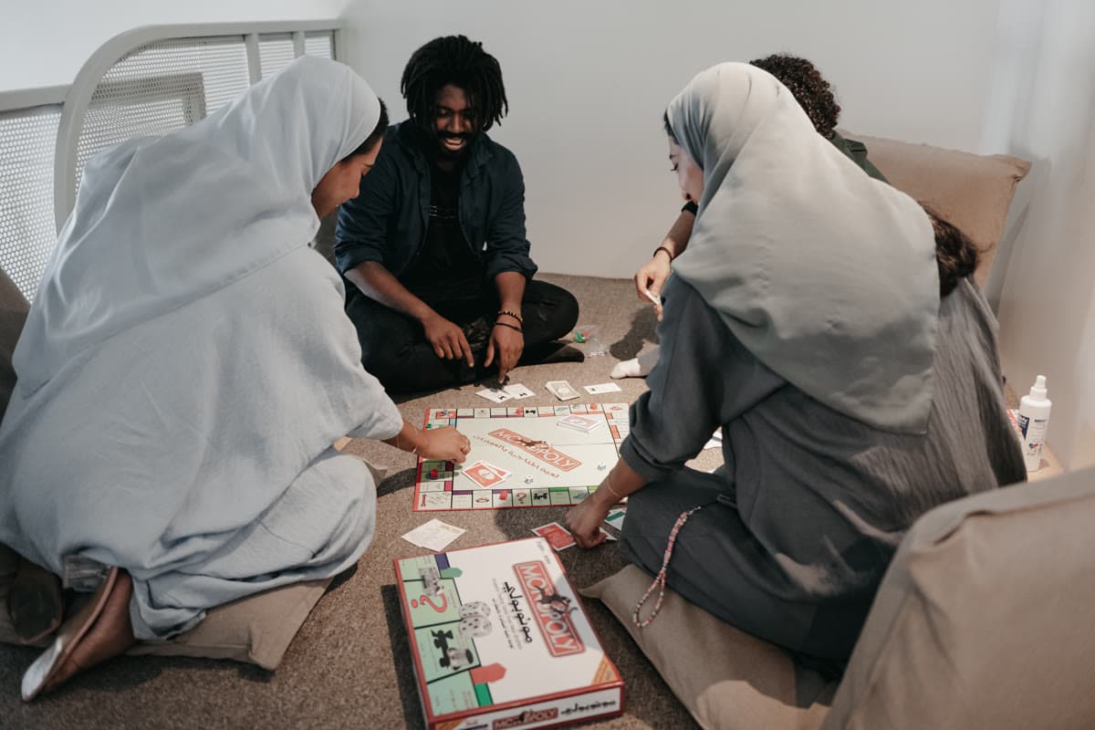 Four people sitting on the floor around a board game at a MAZJ community night