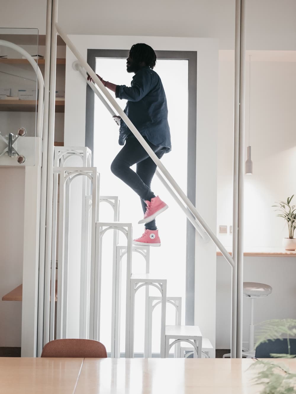 Someone climbing the white staircase inside MAZJ toward a tall window